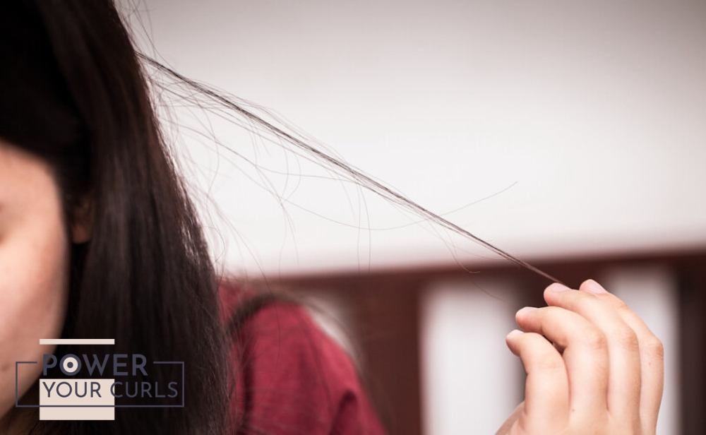 A close-up photo of a girl pulling at her hair strands.