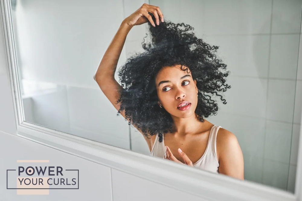 A woman examining her hair in front of a mirror.