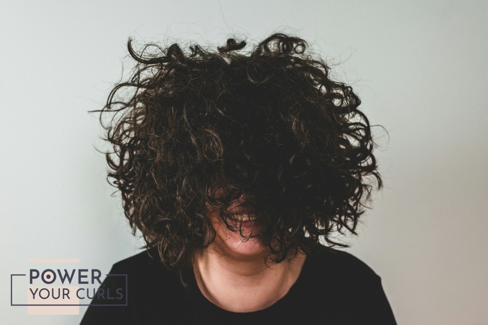 A girl with fluffy, curly hair that covers her eyes.