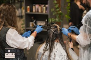 A woman receiving a protein hair treatment at a salon.