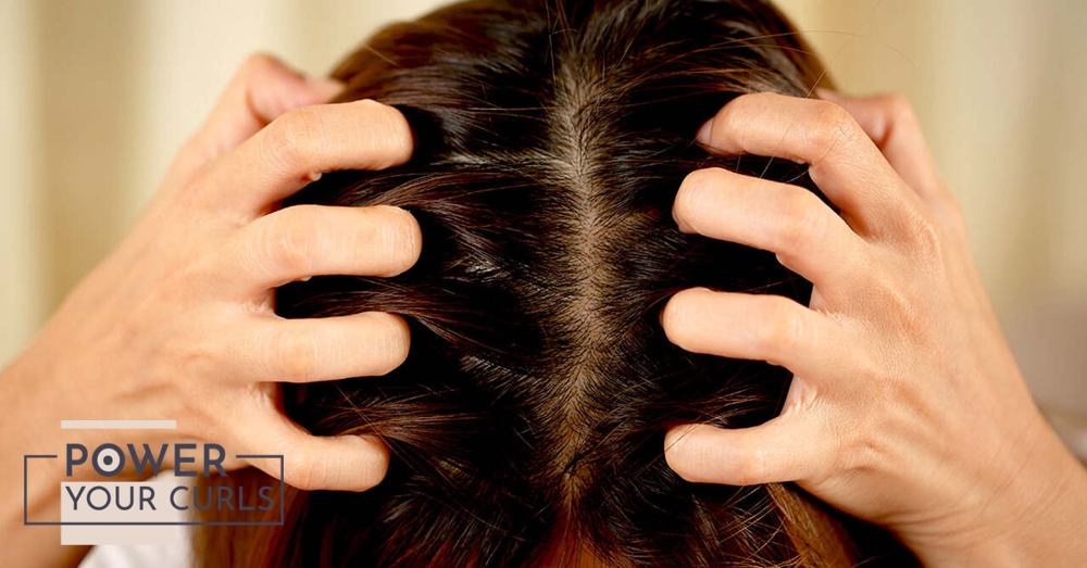 A woman scratching her scalp.