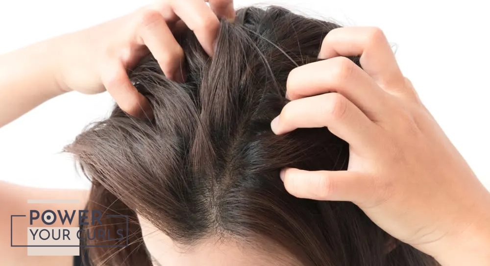 A picture of the top of a woman’s. She is scratching her scalp with both hands.