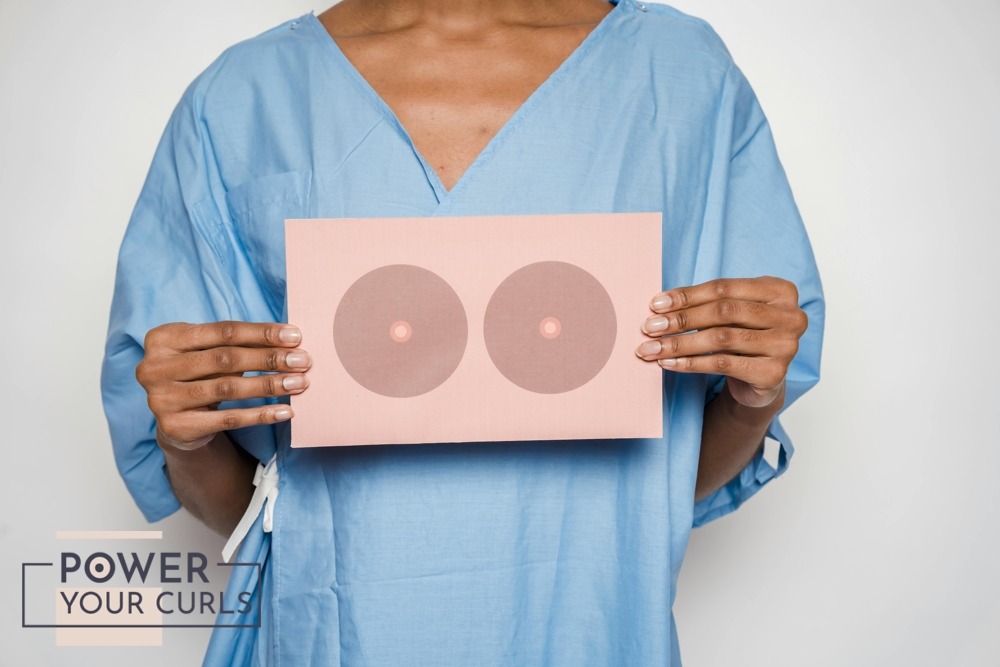 A faceless model wearing a hospital gown and holding an illustration of breasts in front of her chest.