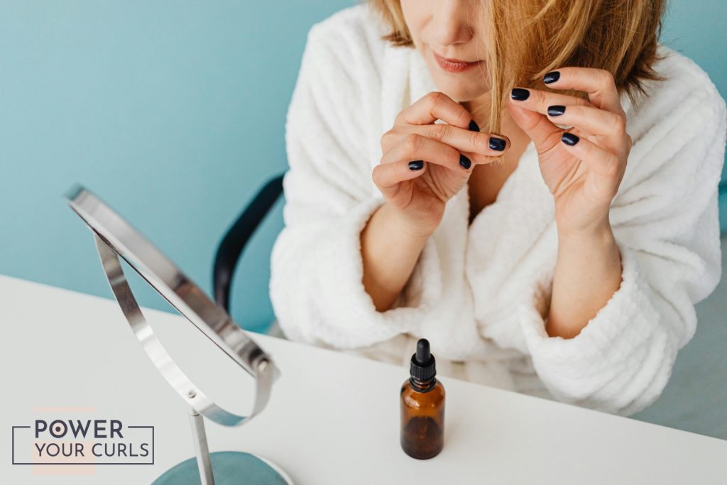 A woman applying product to her hair.