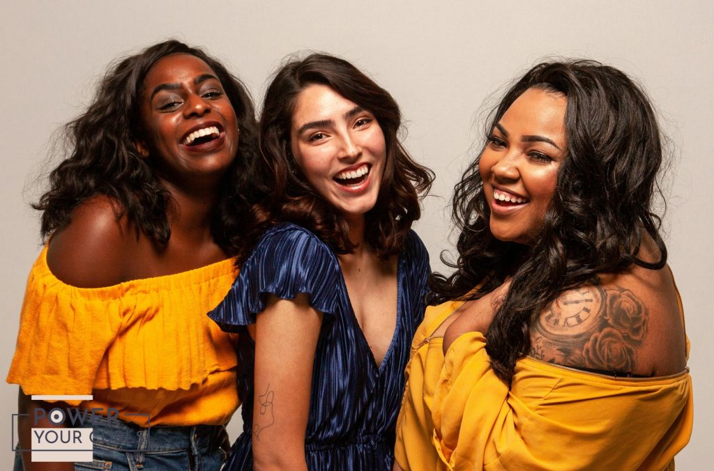 A photo of a group of women with different types of curly and wavy hair, smiling and laughing.