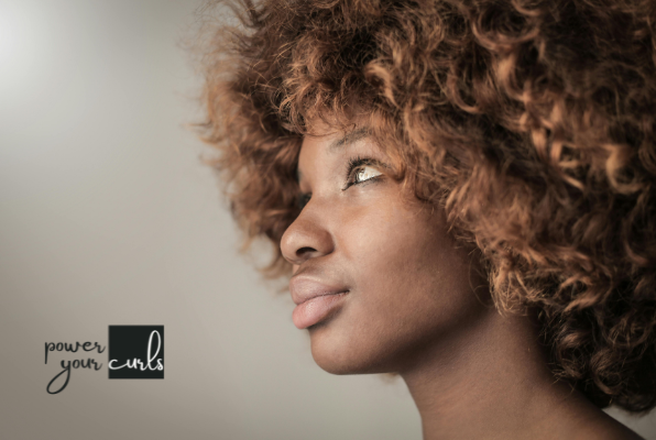 Curly Hair vs. Straight Hair Genetics: Everything You Need to Know 2 A woman with curly hair looking away from the camera.